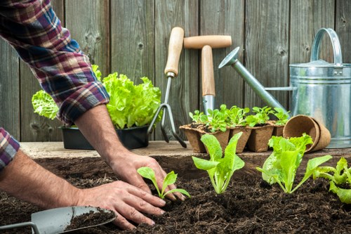 Worker handling garden debris and tools with protective gear